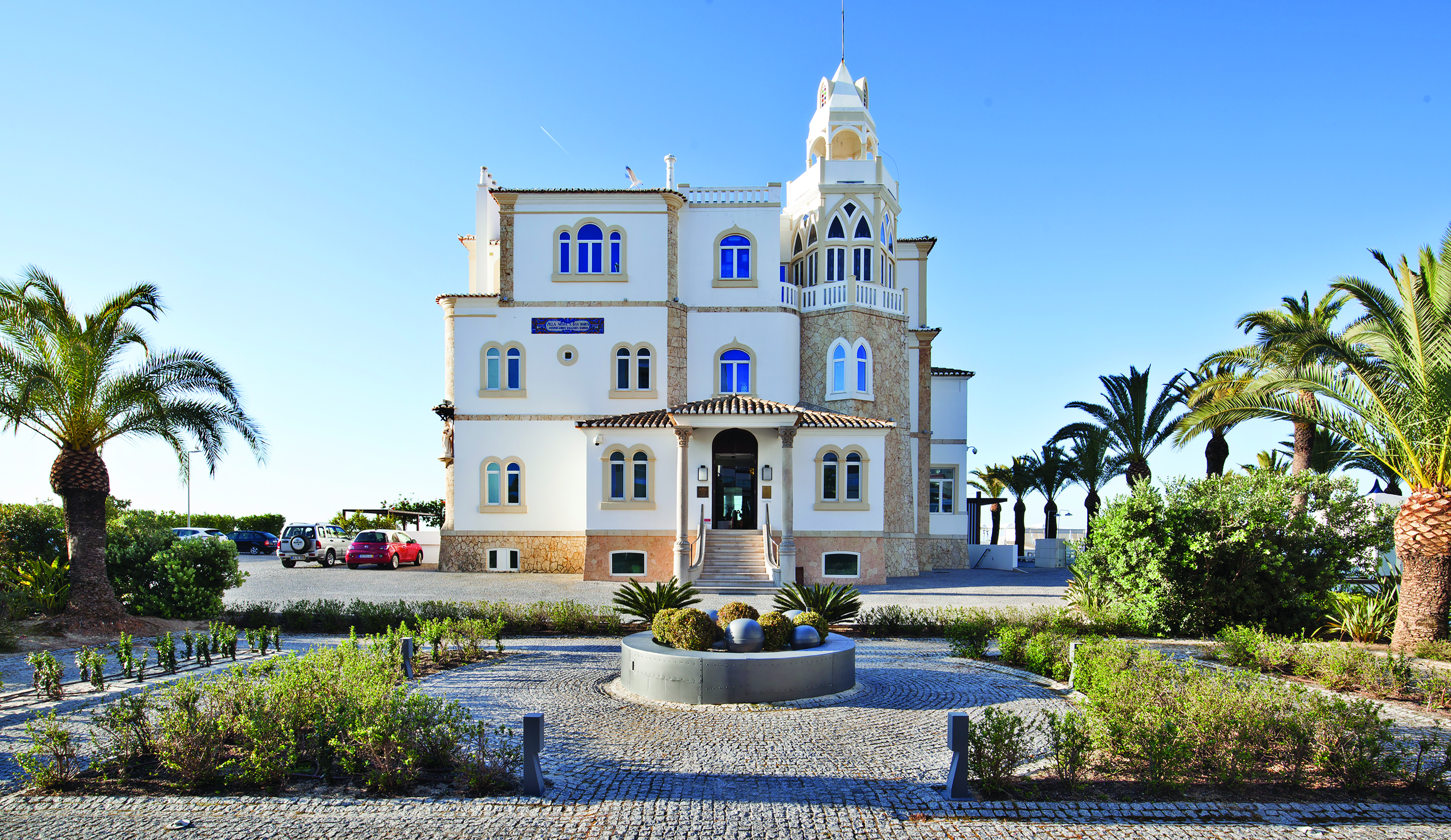 View of the Bela Vista Hotel & Spa from the front with a staircase leading to the hotel entrance and palm trees surrounding the exterior 