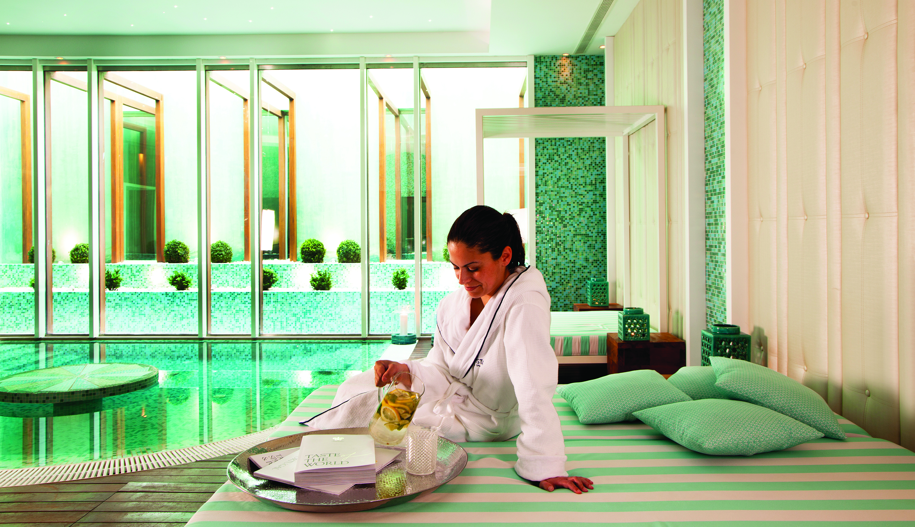 Woman on lounge area drinking lemon water next to plunge pool in spa area of Bela Vista Hotel and Spa