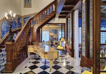 large wooden staircase leading upstairs with blue painting on the walls next to a yellow and blue patterned piano on the ground floor