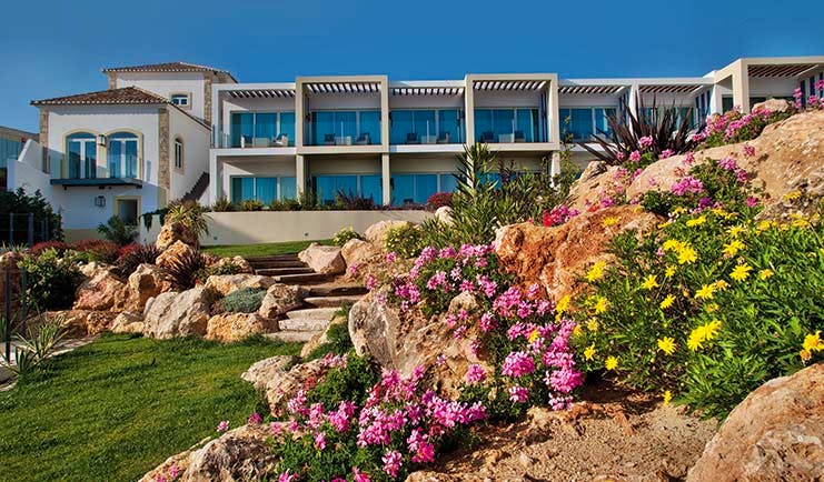 View of the Bela Vista Hotel & Spa from the gardens, displaying green grass and pink and yellow flowers 