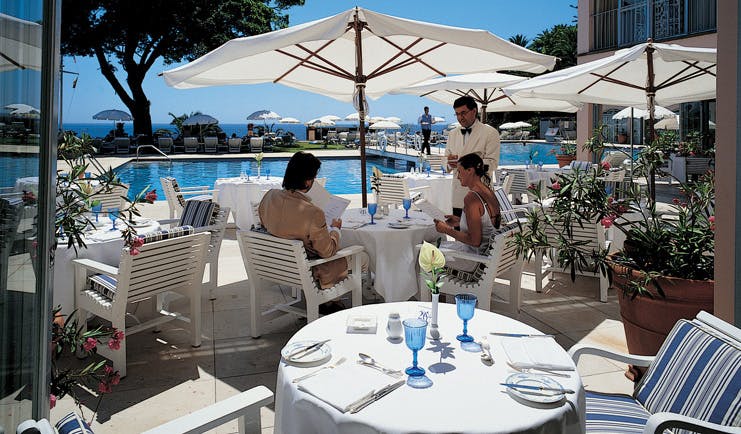 Belmond Reid's Palace Portugal restaurant indoor and outdoor dining area umbrellas pool view