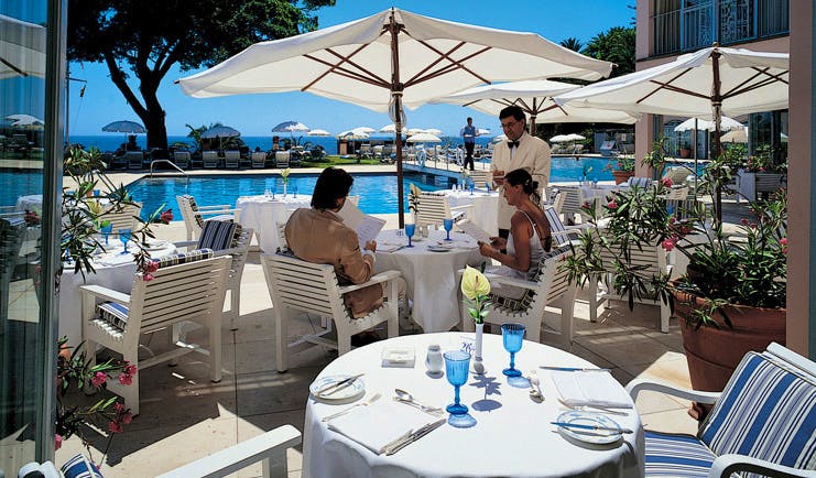 Belmond Reid's Palace Portugal restaurant indoor and outdoor dining area umbrellas pool view