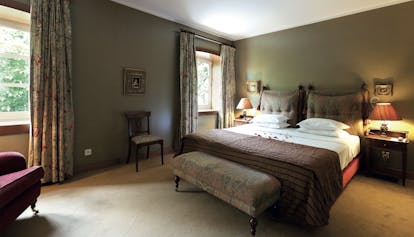 Deluxe room at the casa da calcada with a large double bed, two windows and chairs 
