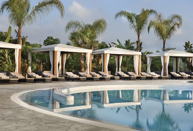 Conrad Algarve poolside cabanas, covered sun loungers next to outdoor pool