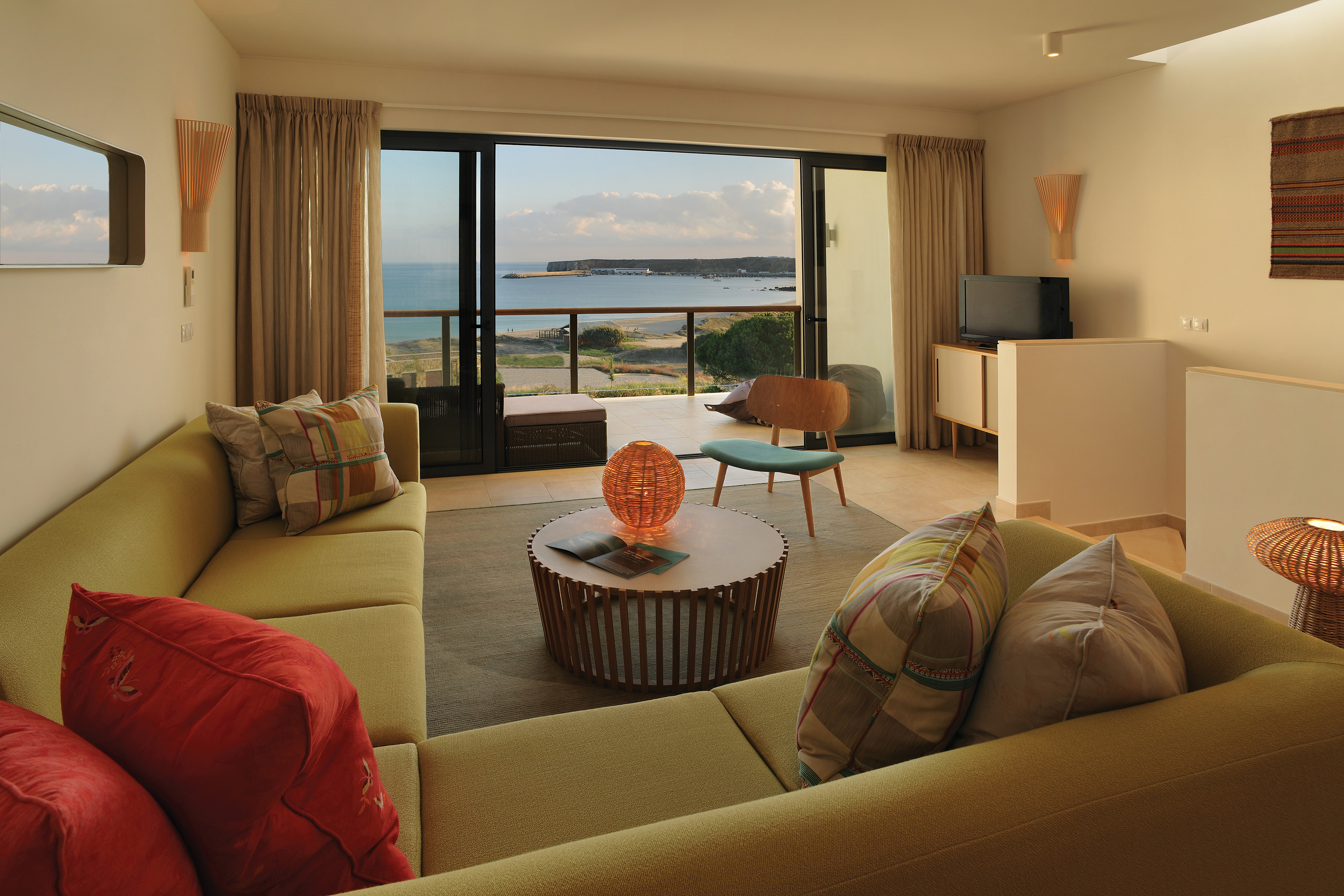 Martinhal Beach Resort and Hotel ocean house room, showing a large corner sofa with bi-folding balcony doors looking over the ocean 