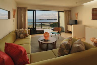 Martinhal Beach Resort and Hotel ocean house room, showing a large corner sofa with bi-folding balcony doors looking over the ocean 