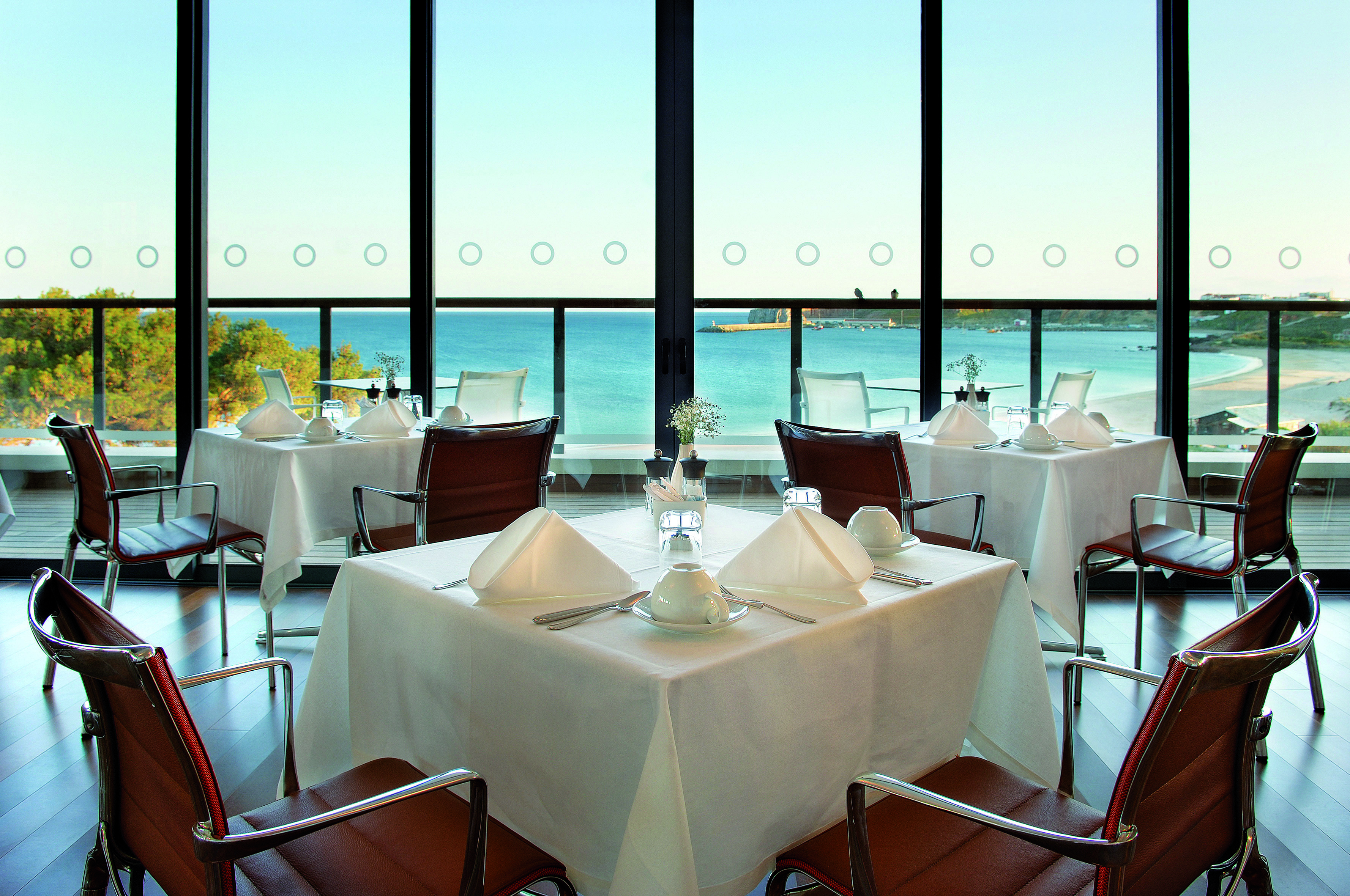 Terrace restaurant at the Martinhal Beach Resort and Hotel, showing dining tables and chairs set out in a room overlooking the sea with big windows