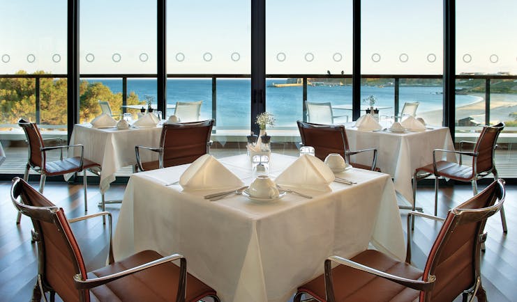 Terrace restaurant at the Martinhal Beach Resort and Hotel, showing dining tables and chairs set out in a room overlooking the sea with big windows