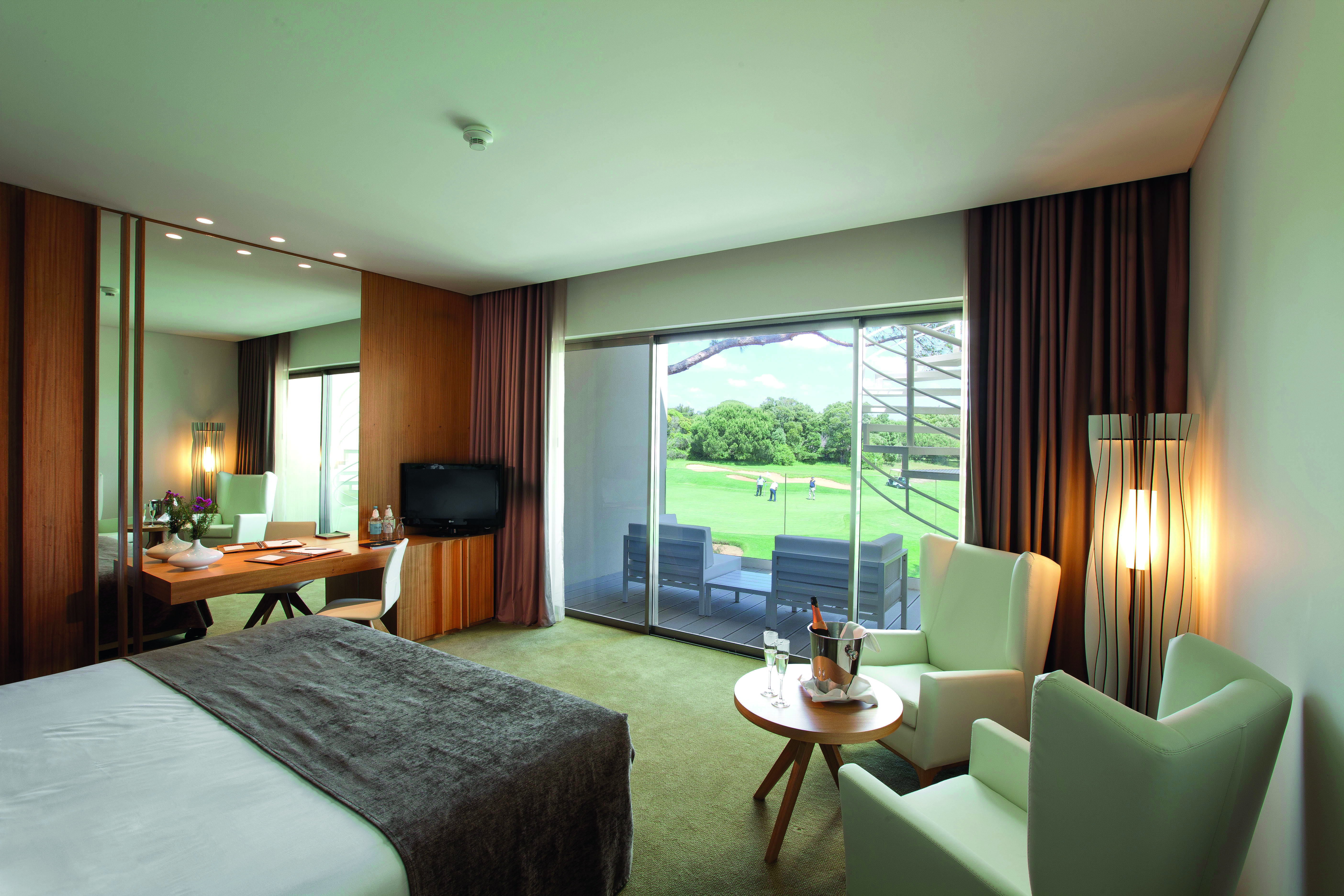 Martinhal Cascais Portugal bedroom golf with two armchairs and desk and patio door to terrace with view of golf course