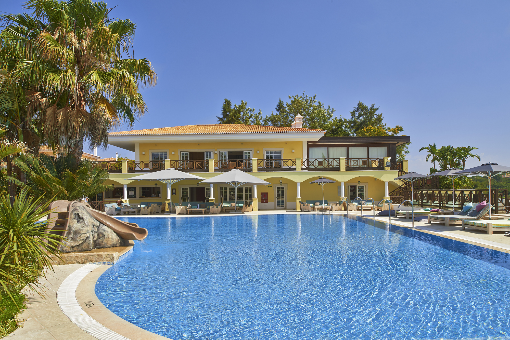 Martinhal Quinta Portugal exterior pool yellow building with arches and balconies overlooking pool with slide