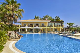 Martinhal Quinta Portugal exterior pool yellow building with arches and balconies overlooking pool with slide