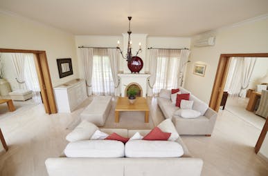 Martinhal Quinta Portugal luxury villa lounge area with sofas armchairs and fireplace with open archways to other rooms