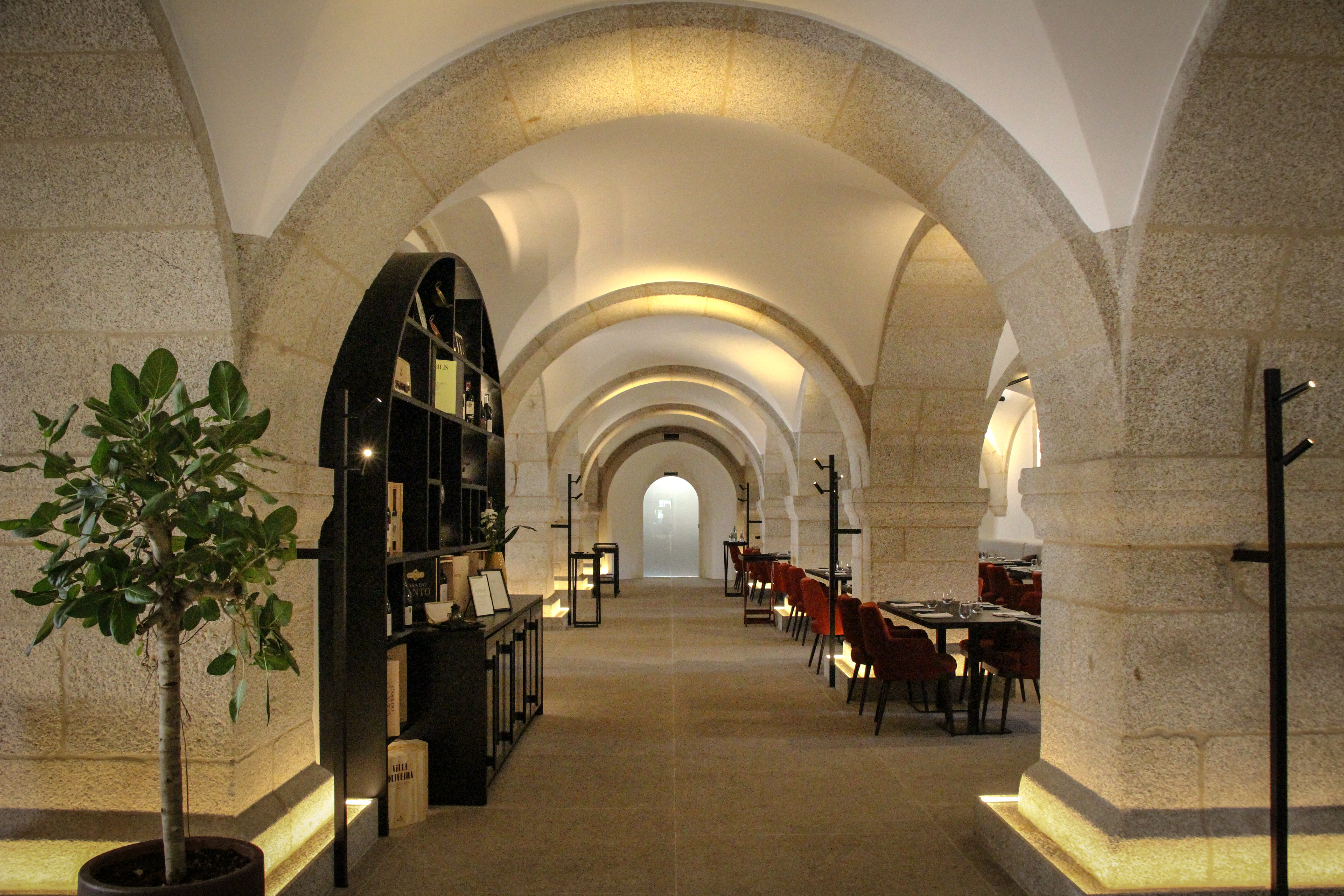 Mosterio de Arouca dining area, with red chairs and black tables scattered beneath stone arches