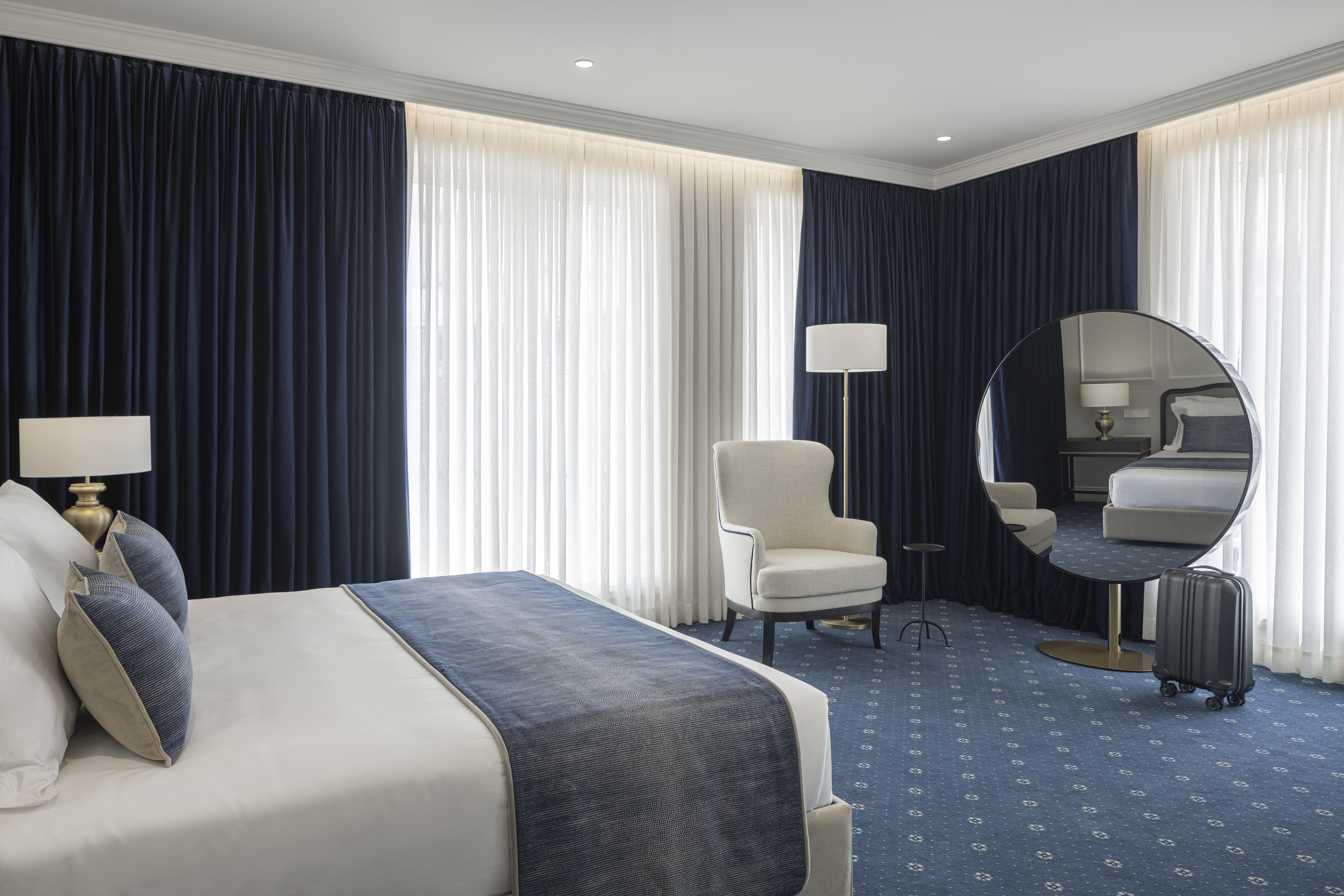Palacete de Valdemouro Classic Room with blue and white design, double bed, large round mirror, and floor-to-ceiling windows on every wall