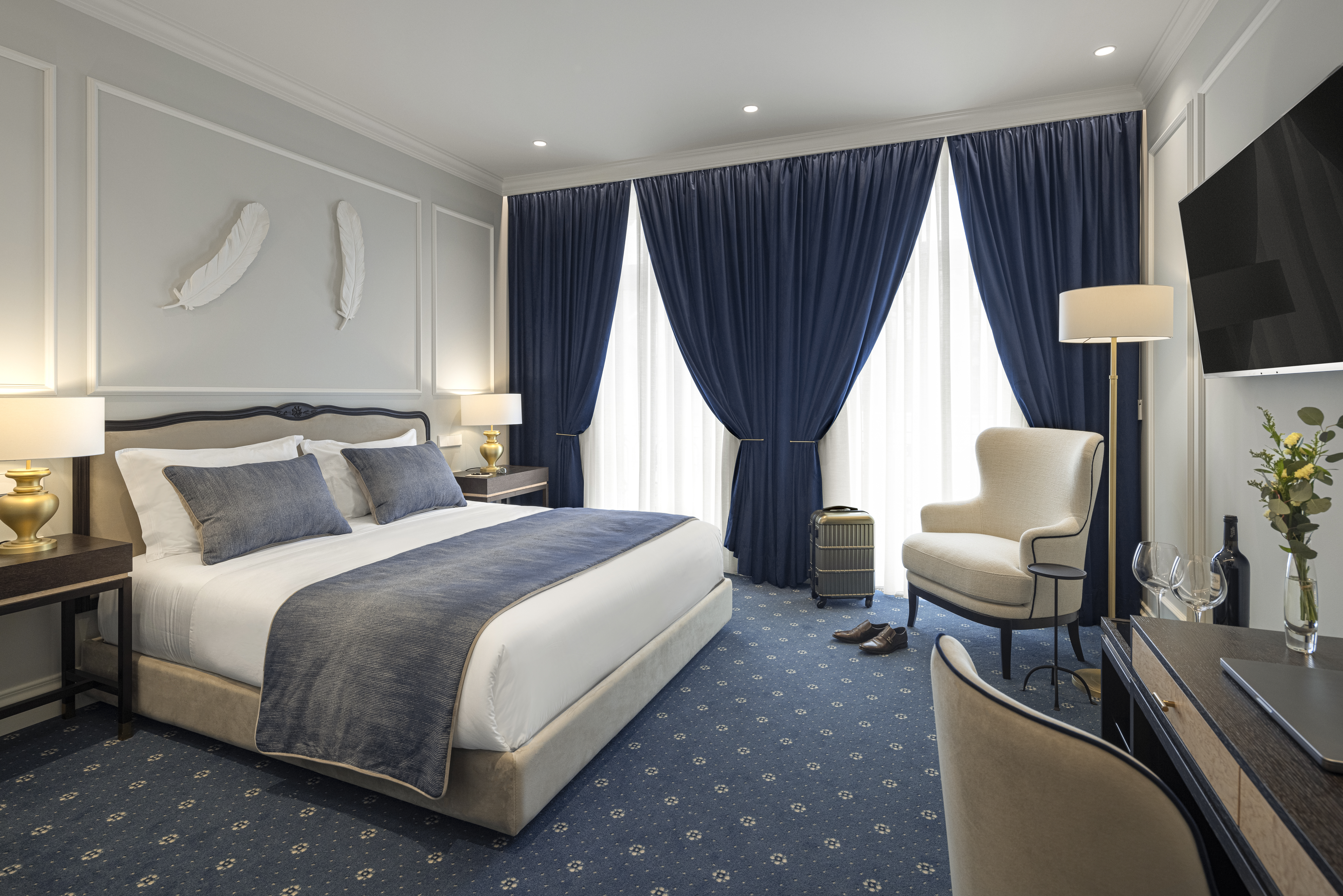 Palacete de Valdemouro Classic Room with blue and white design, double bed, large round mirror, and floor-to-ceiling windows on the far wall