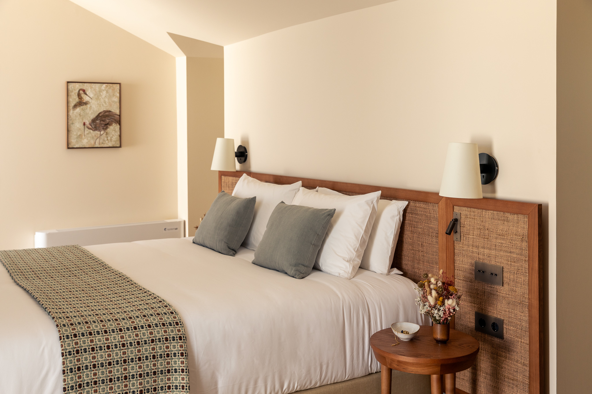 Palacio de Tavira Attic Deluxe room, with neutral colours, white bedsheets, and blue accents
