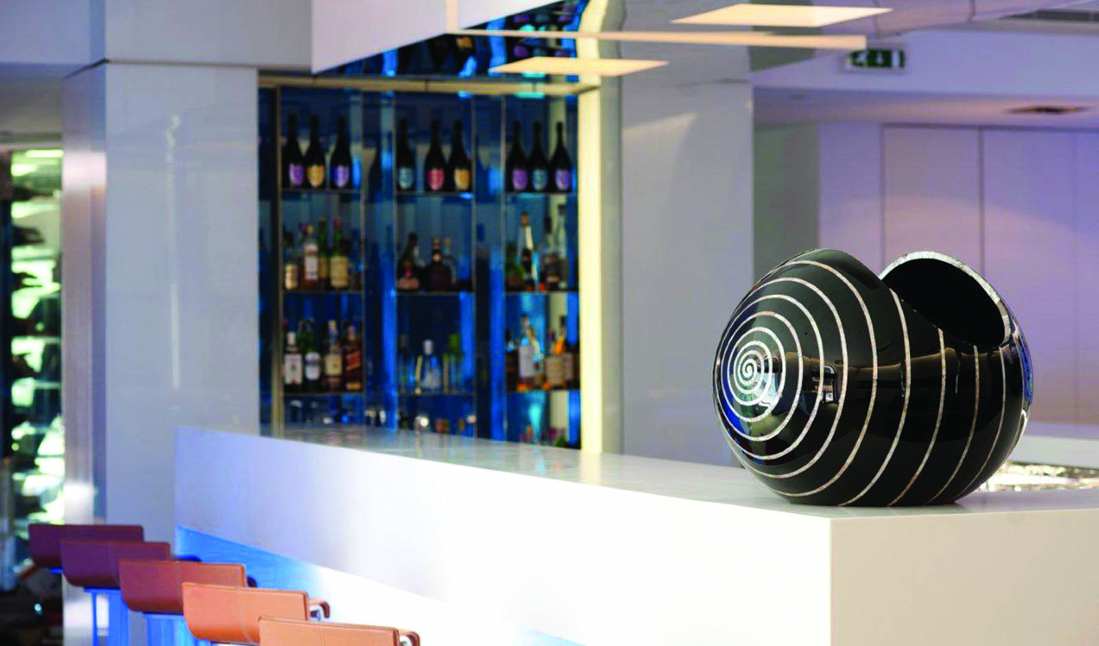 Penha Longa bar with white bar surface, drinks behind the bar, artwork statue on the bar and bar stools