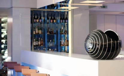 Penha Longa bar with white bar surface, drinks behind the bar, artwork statue on the bar and bar stools
