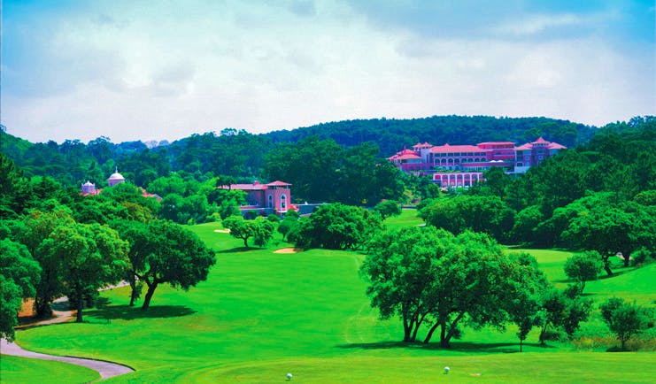 Penha Longa Portugal golf course surrounded by trees and pink building in the distance