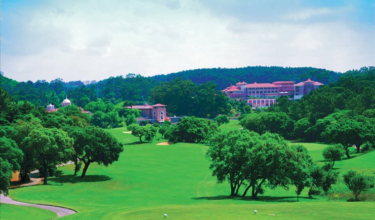 Penha Longa Portugal golf course surrounded by trees and pink building in the distance