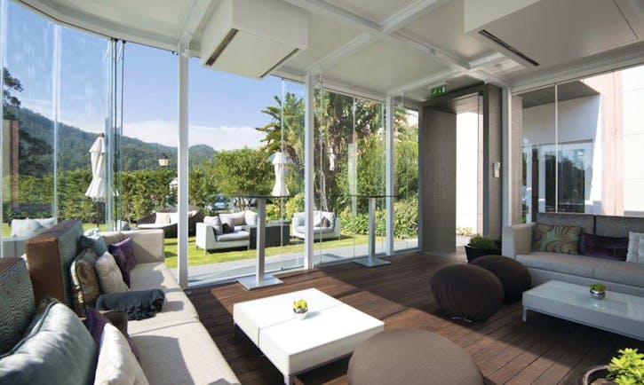 Indoor lounge area with sofas, with bi-folding doors opening onto a terrace with sofas laid out 