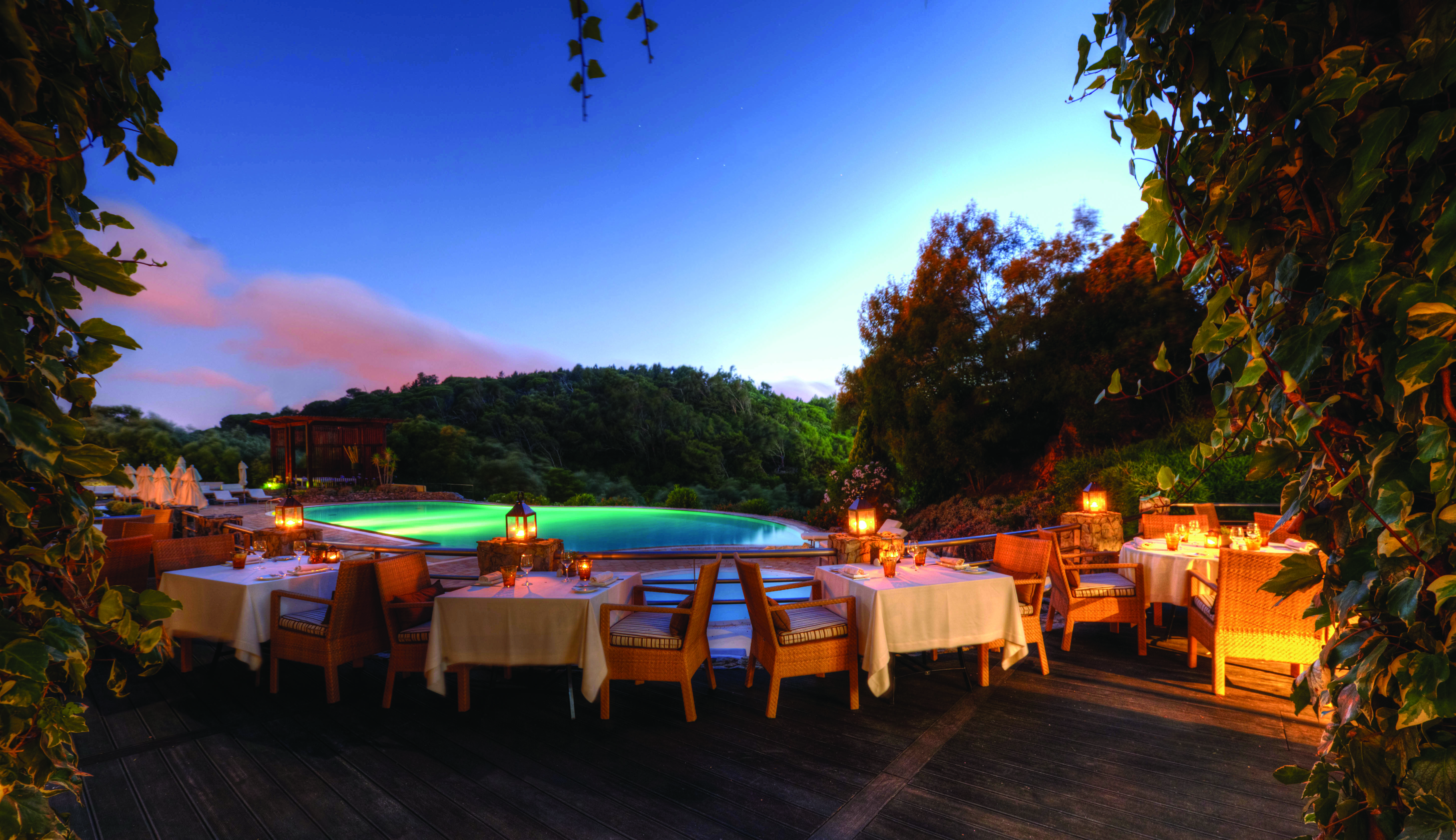 Outdoor dining area of Aqua Restaurant with tables and chairs set up on wooden dekcing looking over the pool 