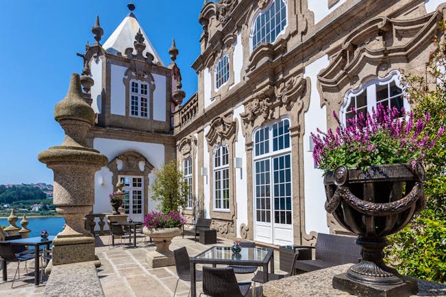 Pestana Palacio do Freixo terrace, outdoor seating area with view over river, grand hotel architecture in background