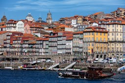 Pestana Vintage Porto exterior, yellow historic building, river bank, boats on the river