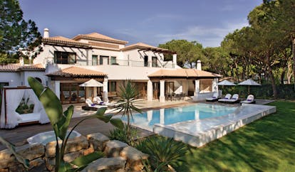 Pine Cliffs Portugal exterior white villa with outdoor pool and sun loungers on deck 