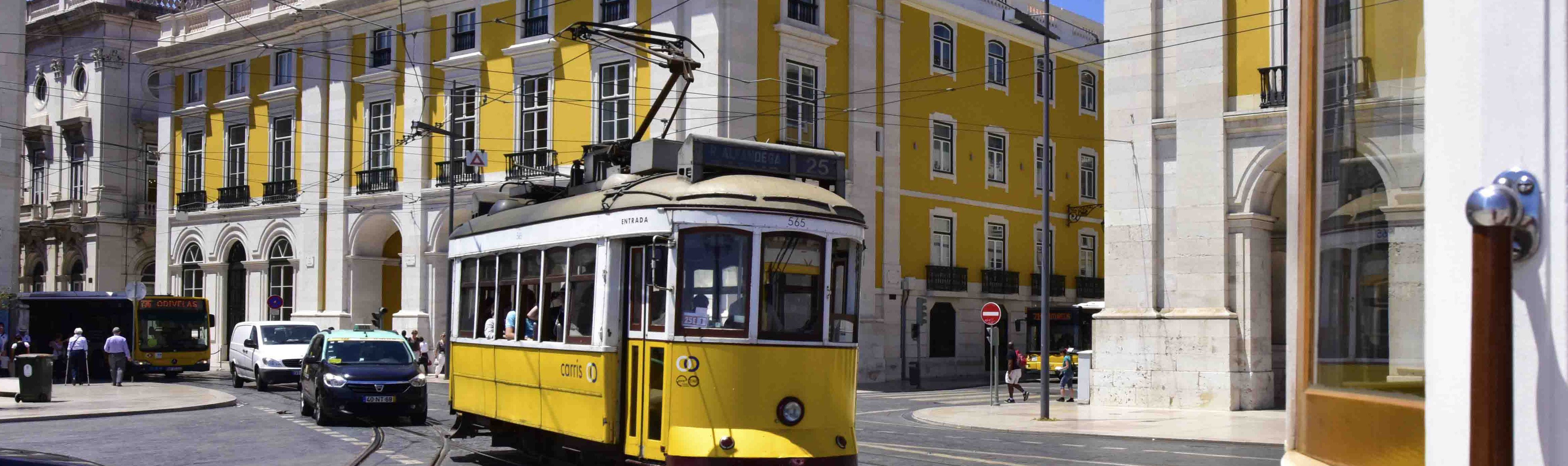 Yellow tram and yellow and white ornate building in Lisbon