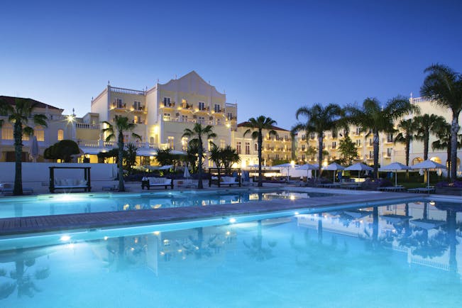 The Lake Spa pool lit up at night, palm trees, hotel building in background