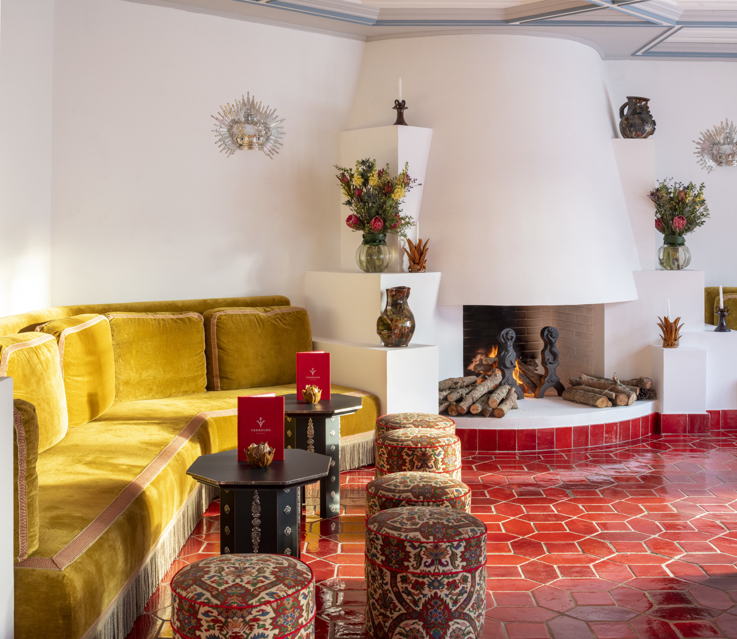 Vermelho Melides Bar with red tiled floor, low rounded fireplace, and booth-like seating along the walls