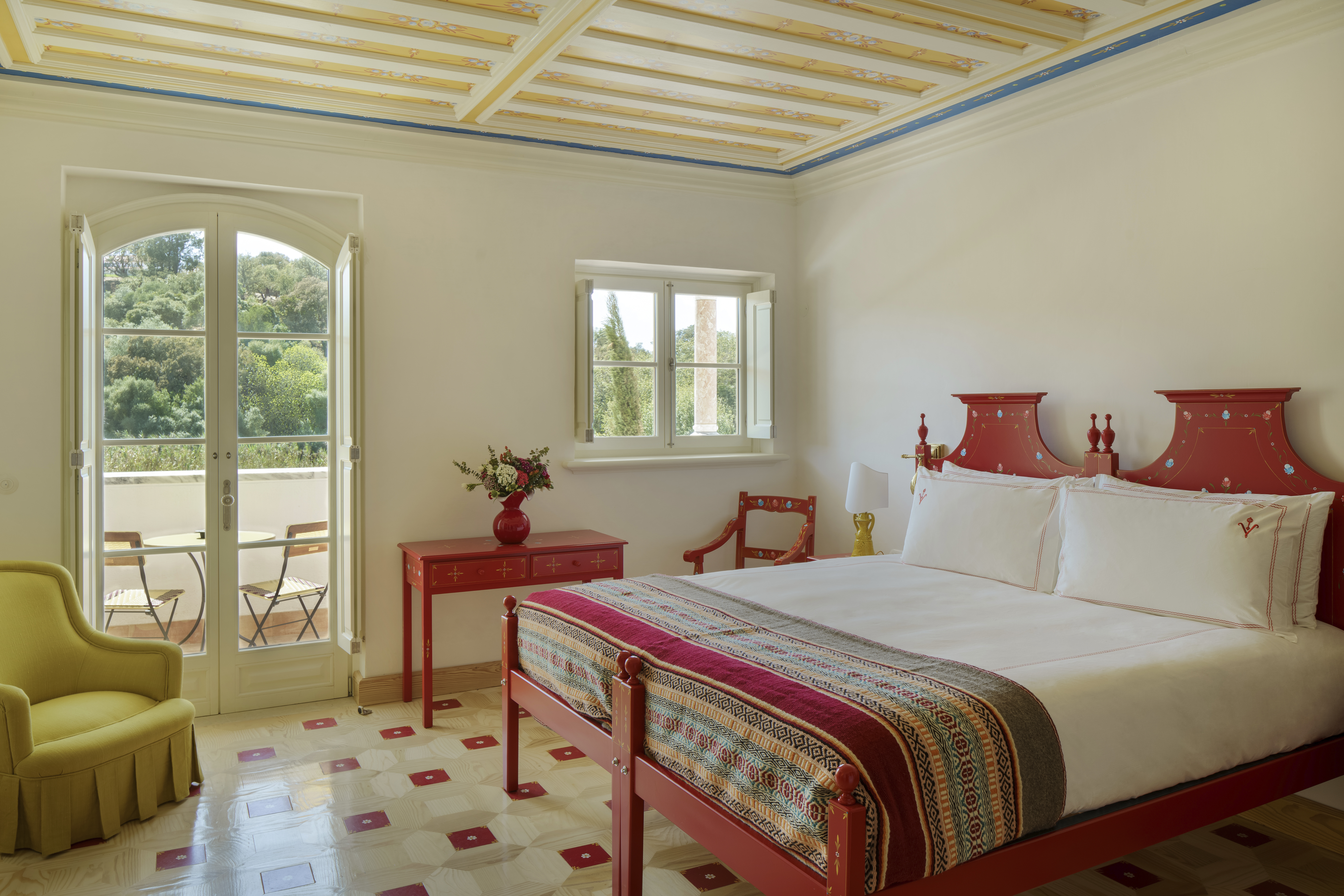 Vermelho Melides Vista Verde Room with pink framed bed, light green armchair, and patterned tiled floor