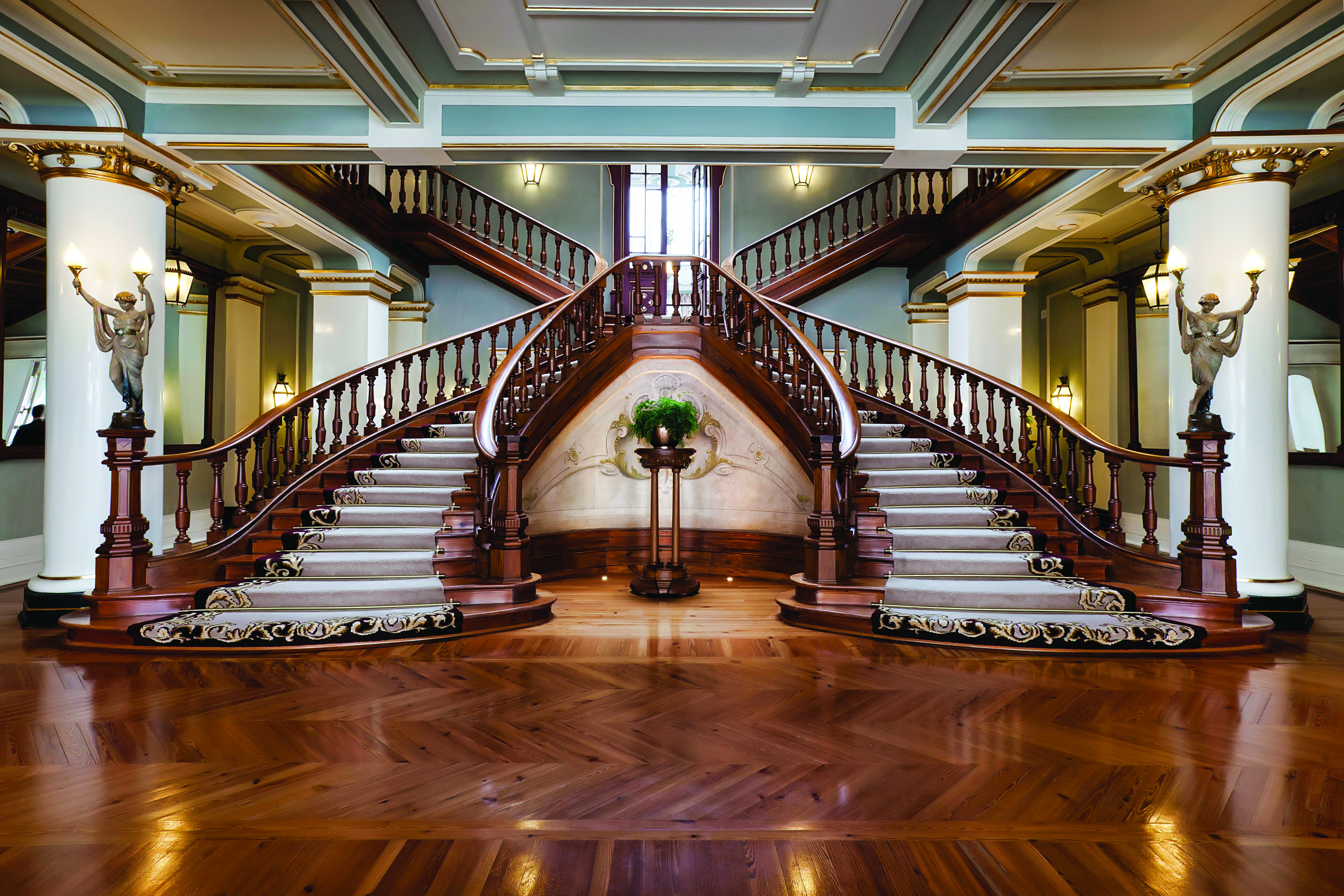 Vidago Palace Portugal lobby staircases ornate wooden twin staircases with statues of women at the foot