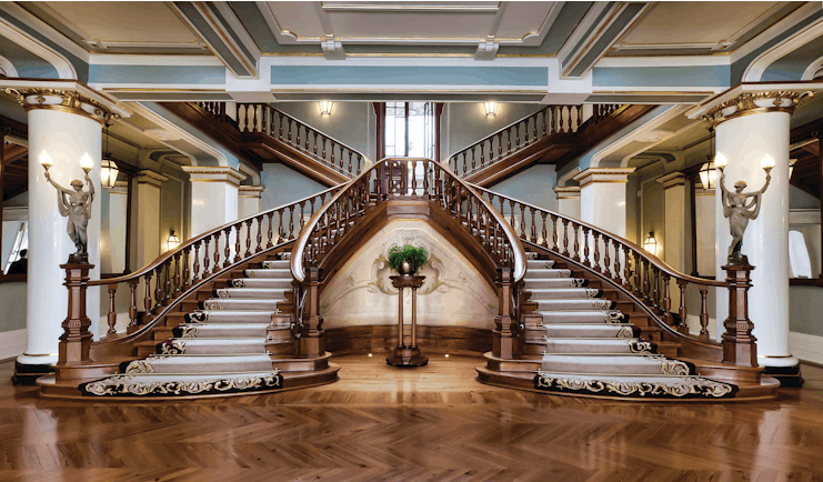 Vidago Palace Portugal lobby staircases ornate wooden twin staircases with statues of women at the foot