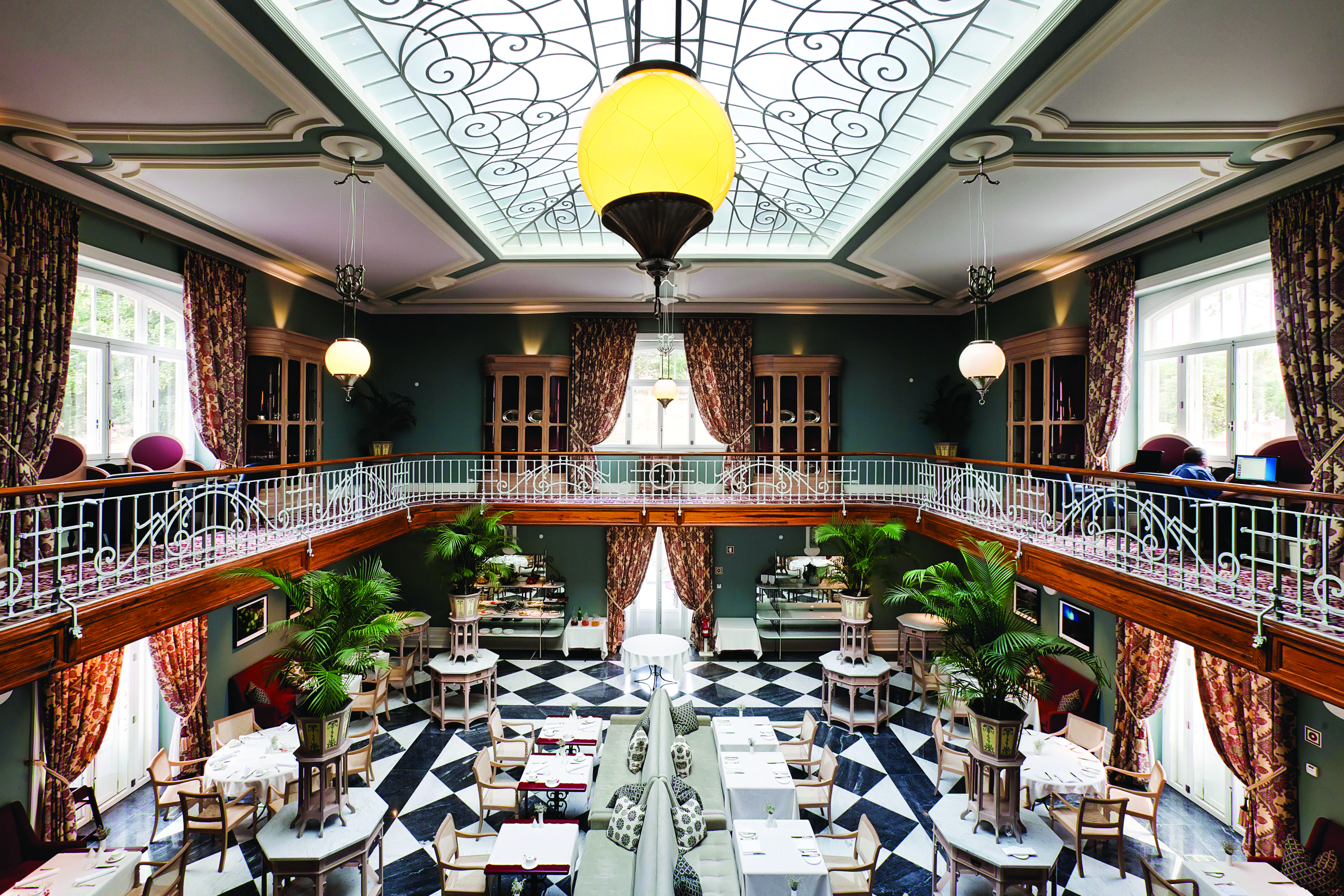 Vidago Palace Portugal winter garden restaurant indoor dining room with balcony glass ceiling and black and white tiles