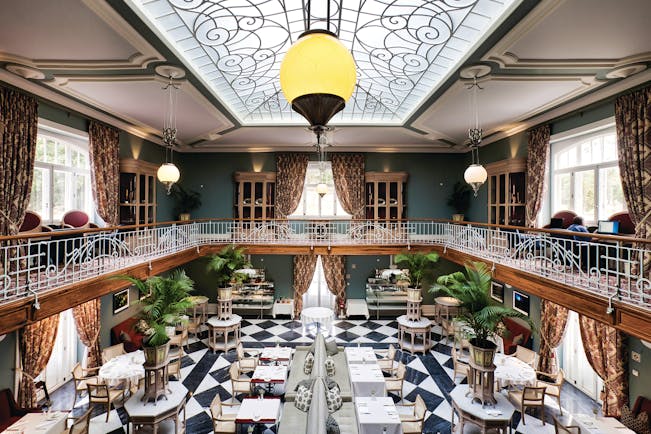 Vidago Palace Portugal winter garden restaurant indoor dining room with balcony glass ceiling and black and white tiles