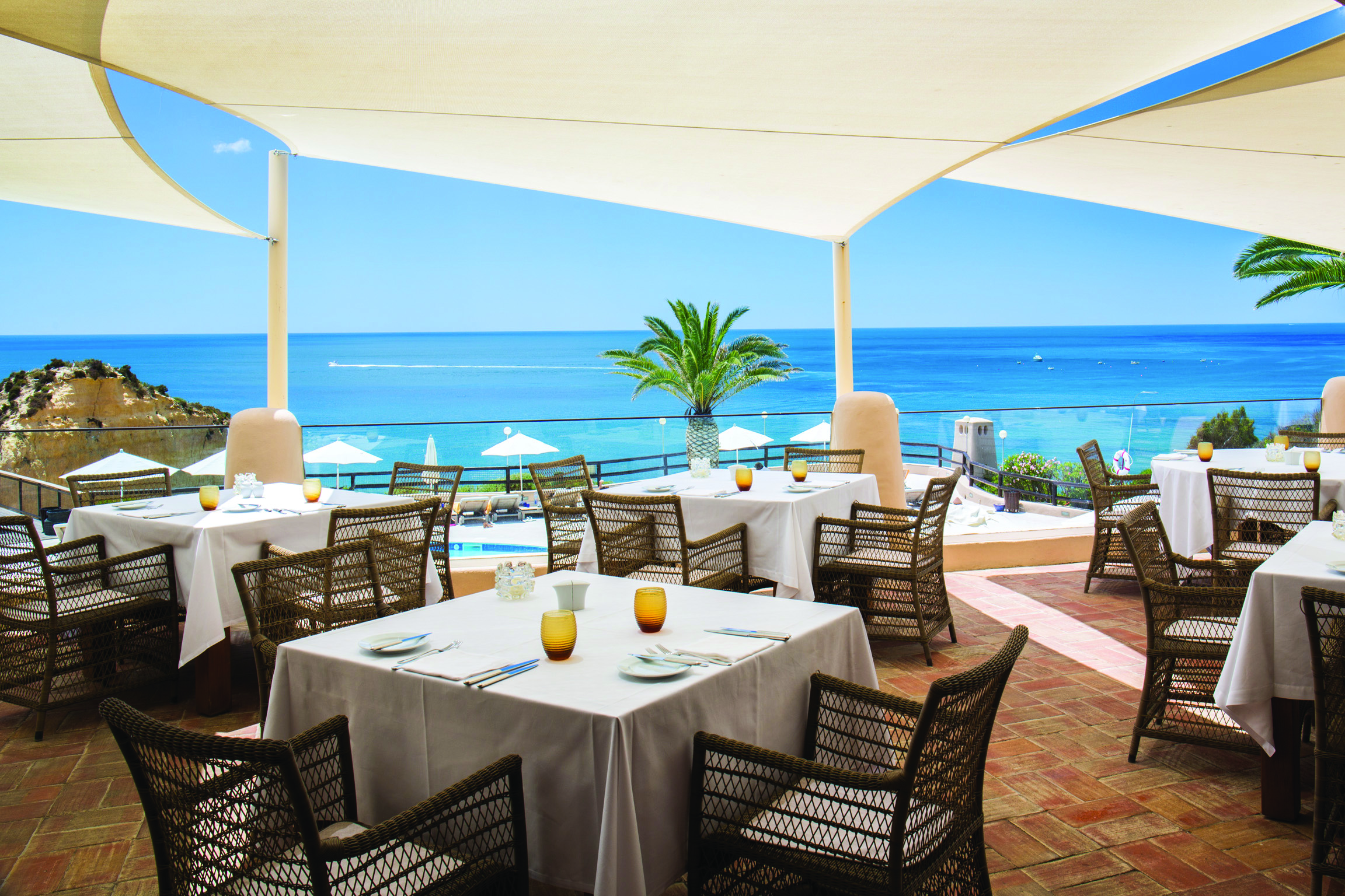 dining area restaurant with tables and chairs set out on a terrace overlooking the pool and beach 