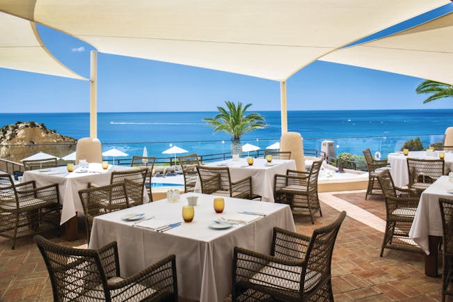 dining area restaurant with tables and chairs set out on a terrace overlooking the pool and beach 