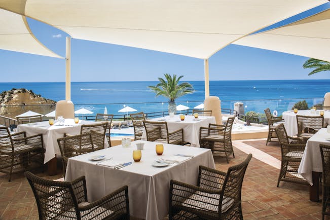 dining area restaurant with tables and chairs set out on a terrace overlooking the pool and beach 