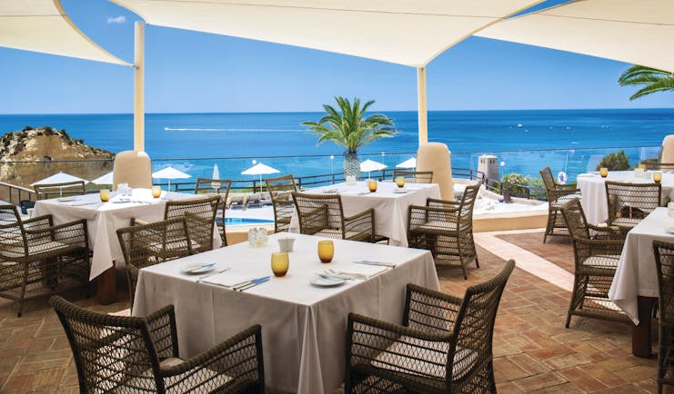 dining area restaurant with tables and chairs set out on a terrace overlooking the pool and beach 
