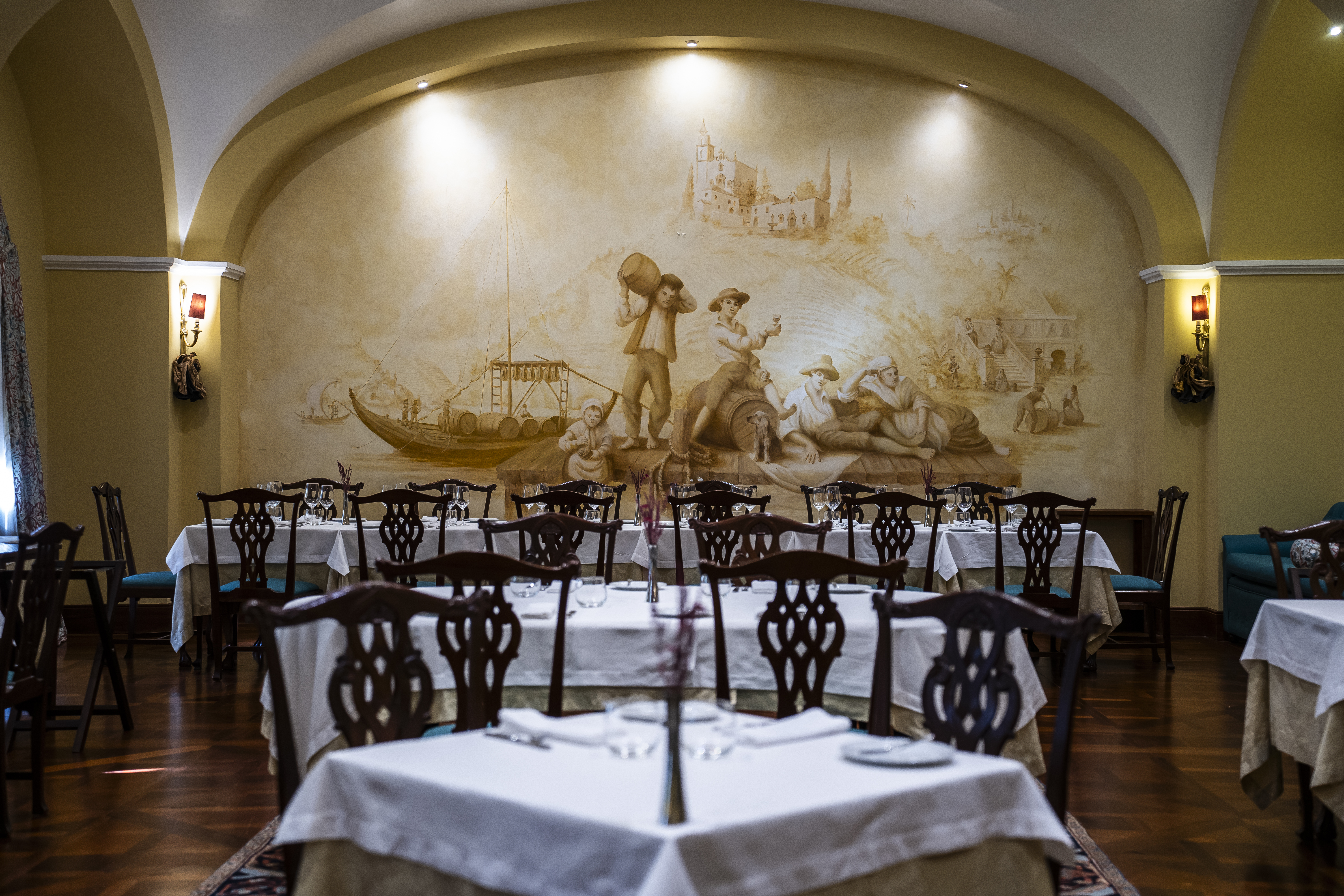 Vintage House Pinhao Rabelo Restaurant, with white-clothed tables, ornate dark wood chairs, arched ceiling and pillars, and a classical mural on the far wall