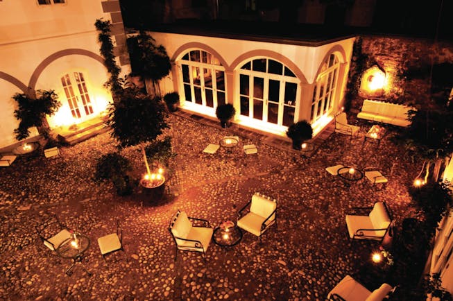 Antiq Palace Hotel Ljubljana courtyard at night time with several chairs and sofas