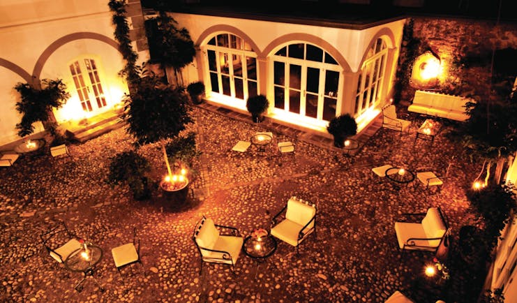 Antiq Palace Hotel Ljubljana courtyard at night time with several chairs and sofas