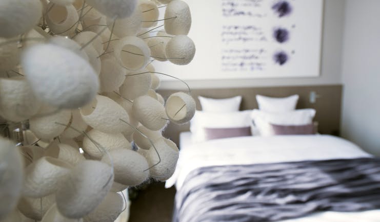 Hotel Cubo guestroom, focus on fake flower installation, double bed, painting, bright modern decor