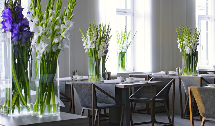 Hotel Cubo restaurant, tables ad chairs, fresh flowers in vases, white bright decor
