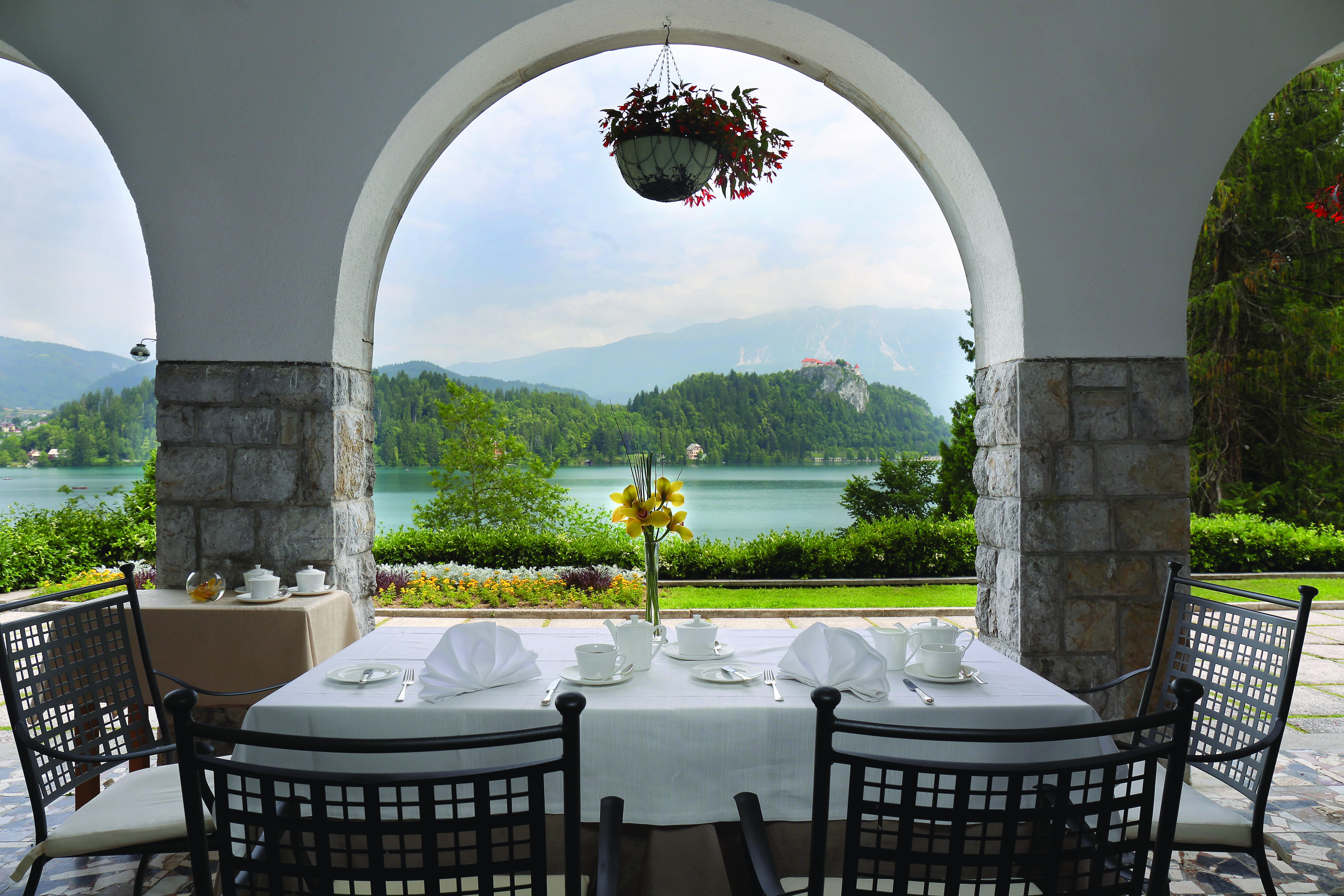 Vila Bled terrace with table and chairs looking through a stone archway onto the lake 