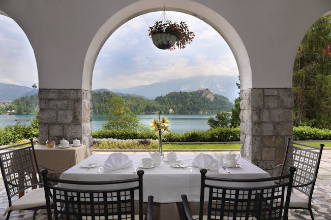 Vila Bled terrace with table and chairs looking through a stone archway onto the lake 