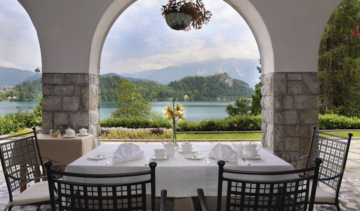 Vila Bled terrace with table and chairs looking through a stone archway onto the lake 