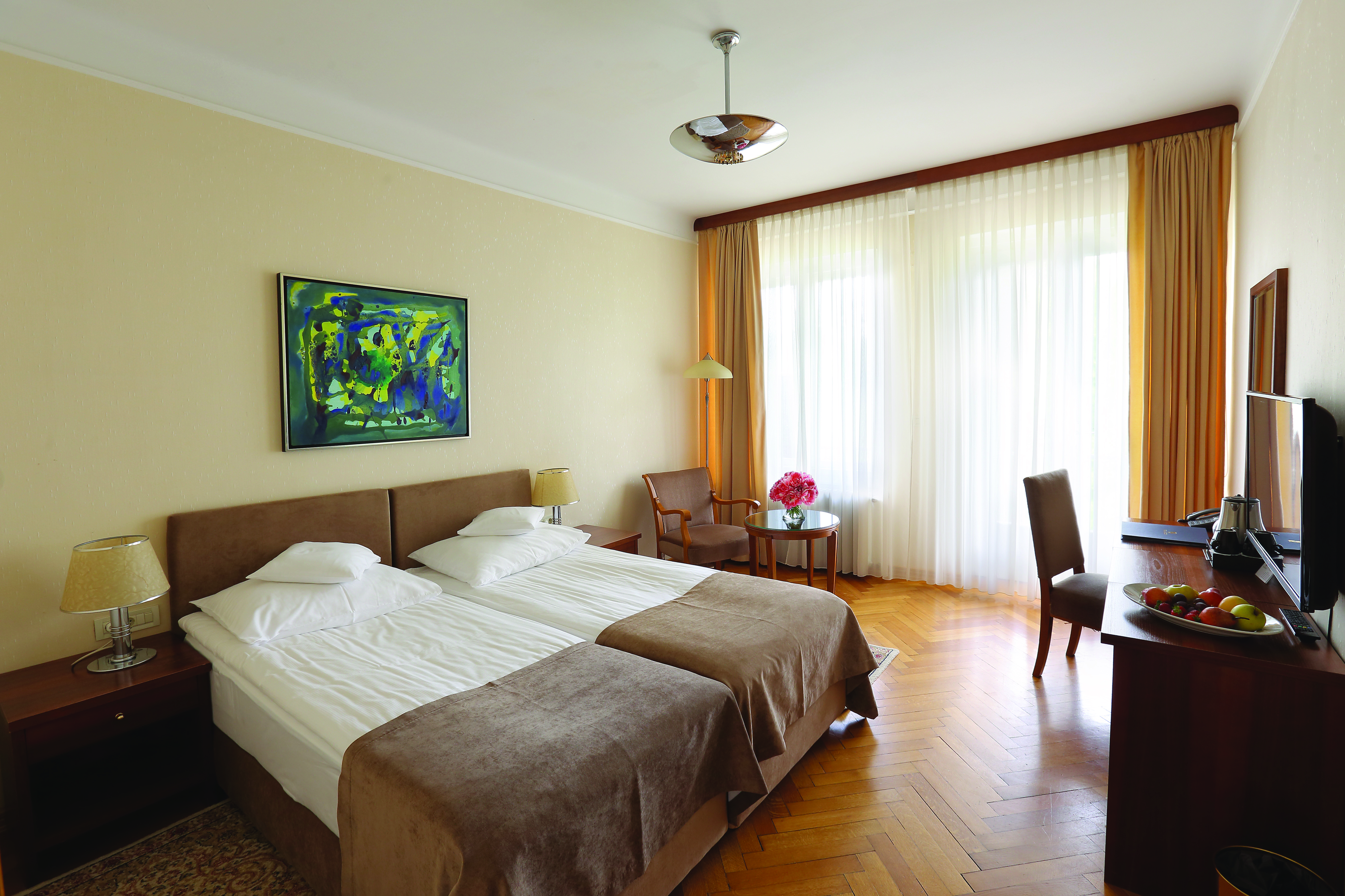 Double room with balcony at the Vila Bled hotel, with a neutral colour scheme and television 